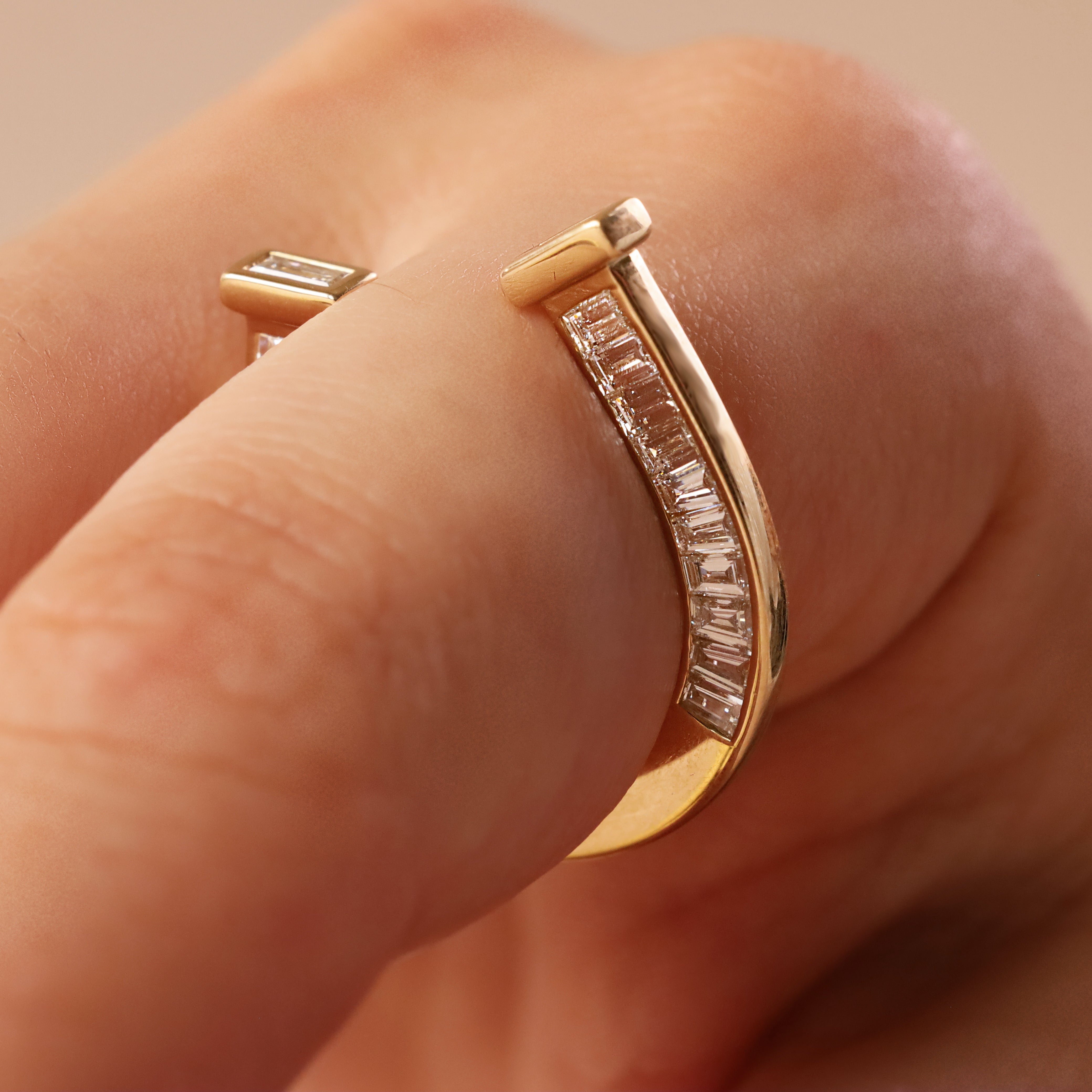close up of horseshoe ring with baguette diamonds on finger