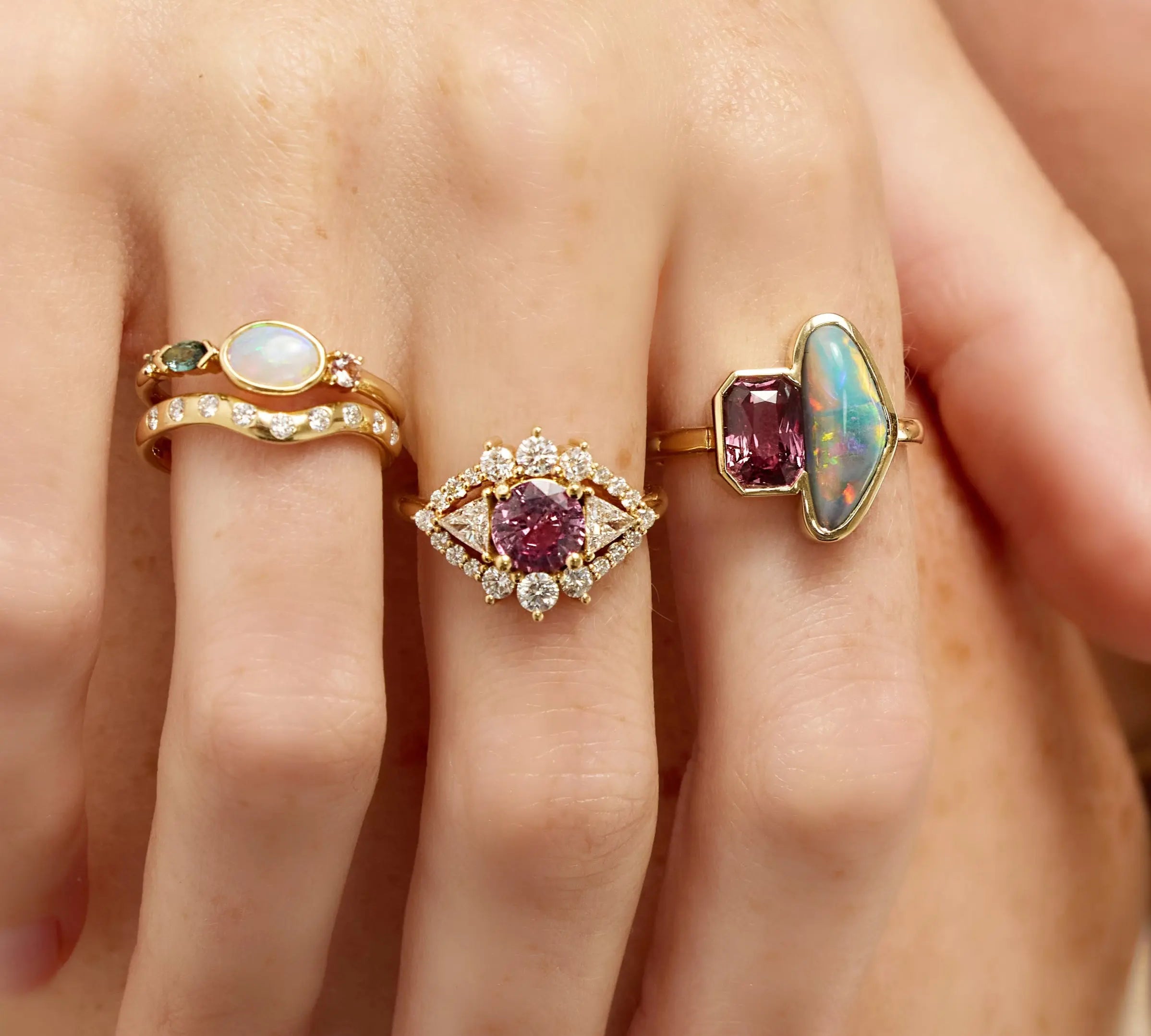 Three gold rings with gemstones on a hand