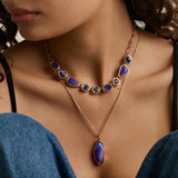 close up of woman's décolletage showcasing two statement blue gemstone necklaces layered together