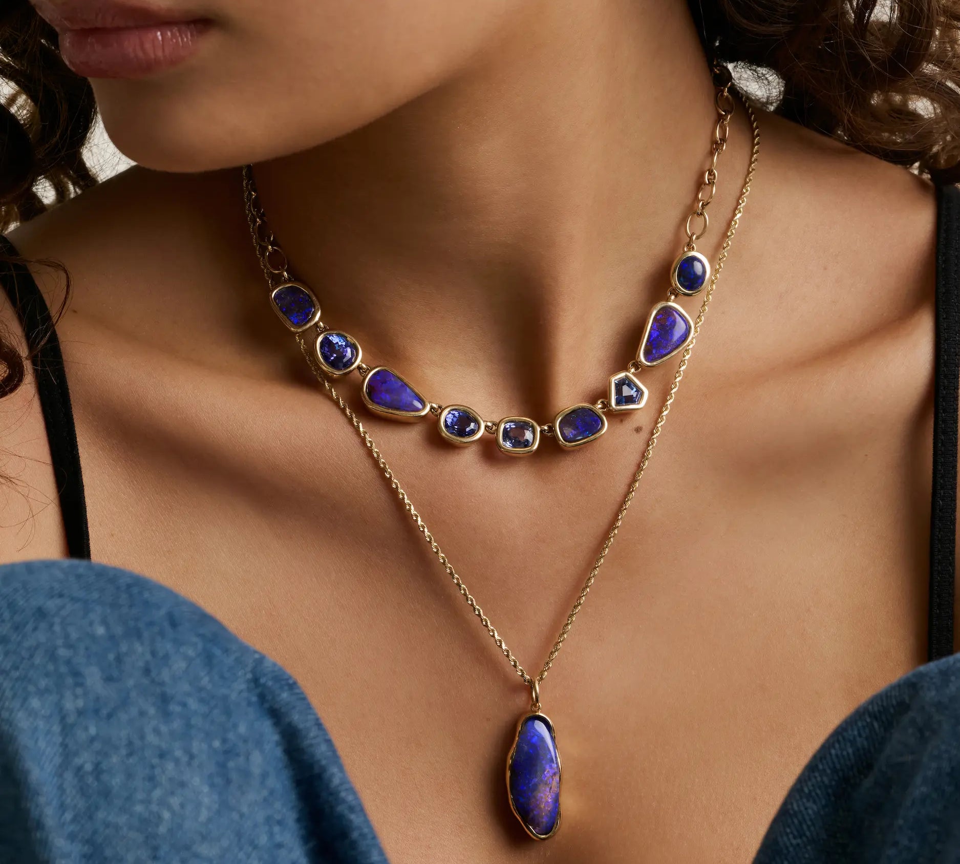 close up of woman's décolletage showcasing two statement blue gemstone necklaces layered together