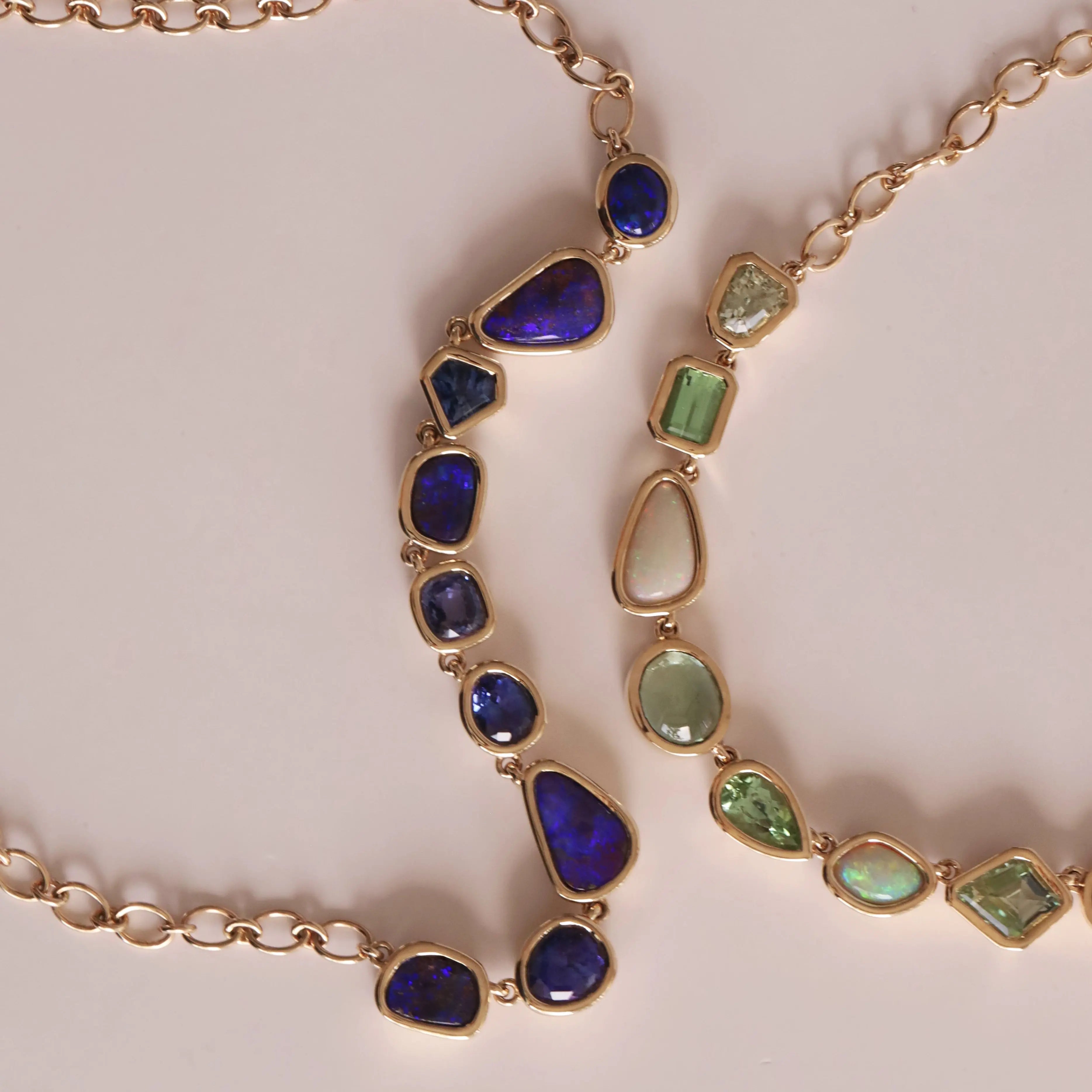 Gold necklace with blue and green gemstones on a light background