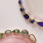 Necklace with multicolored gemstones on a soft pink background