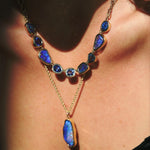 Necklace with blue gemstones and gold chain worn by a person