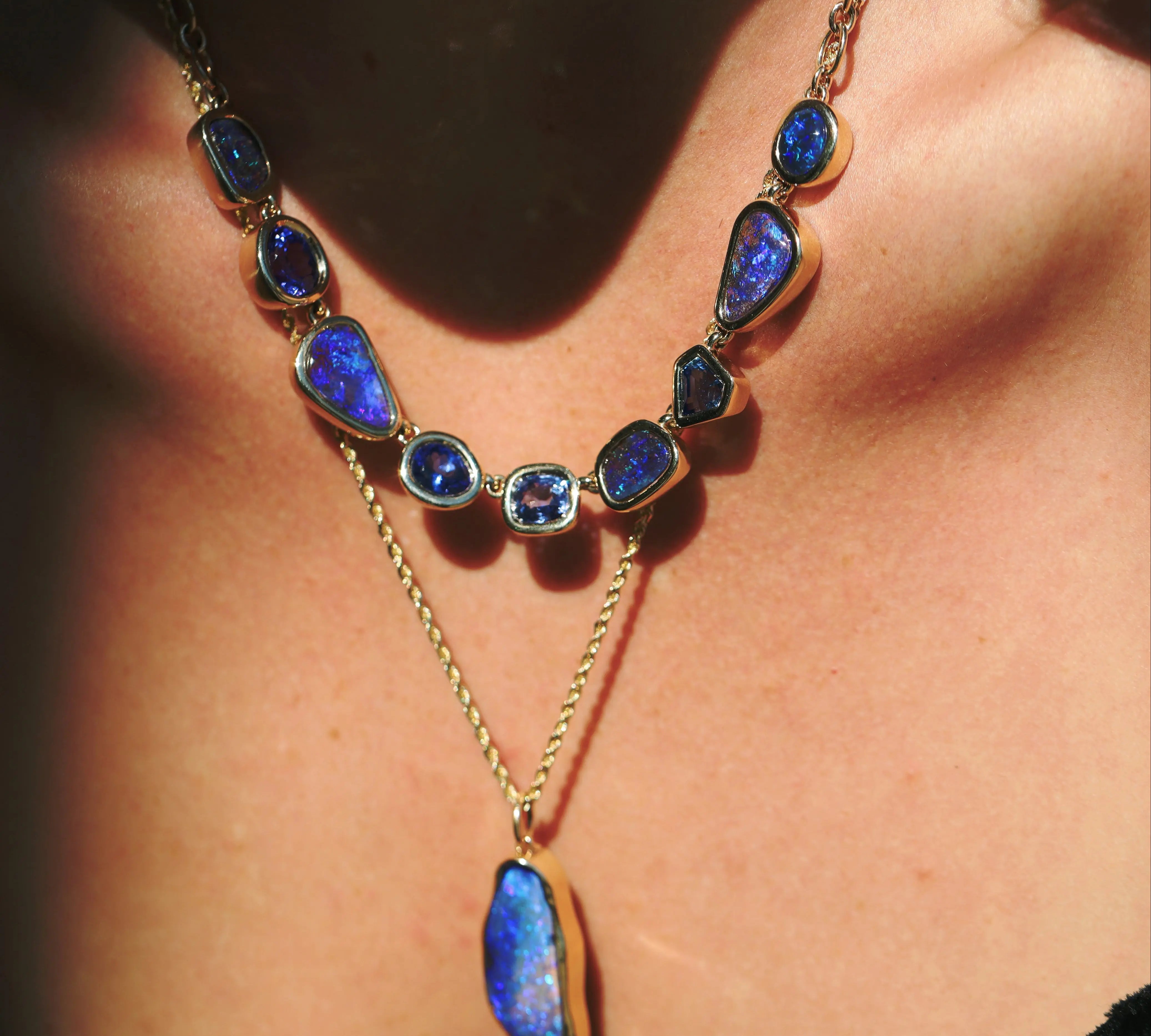 Necklace with blue gemstones and gold chain worn by a person