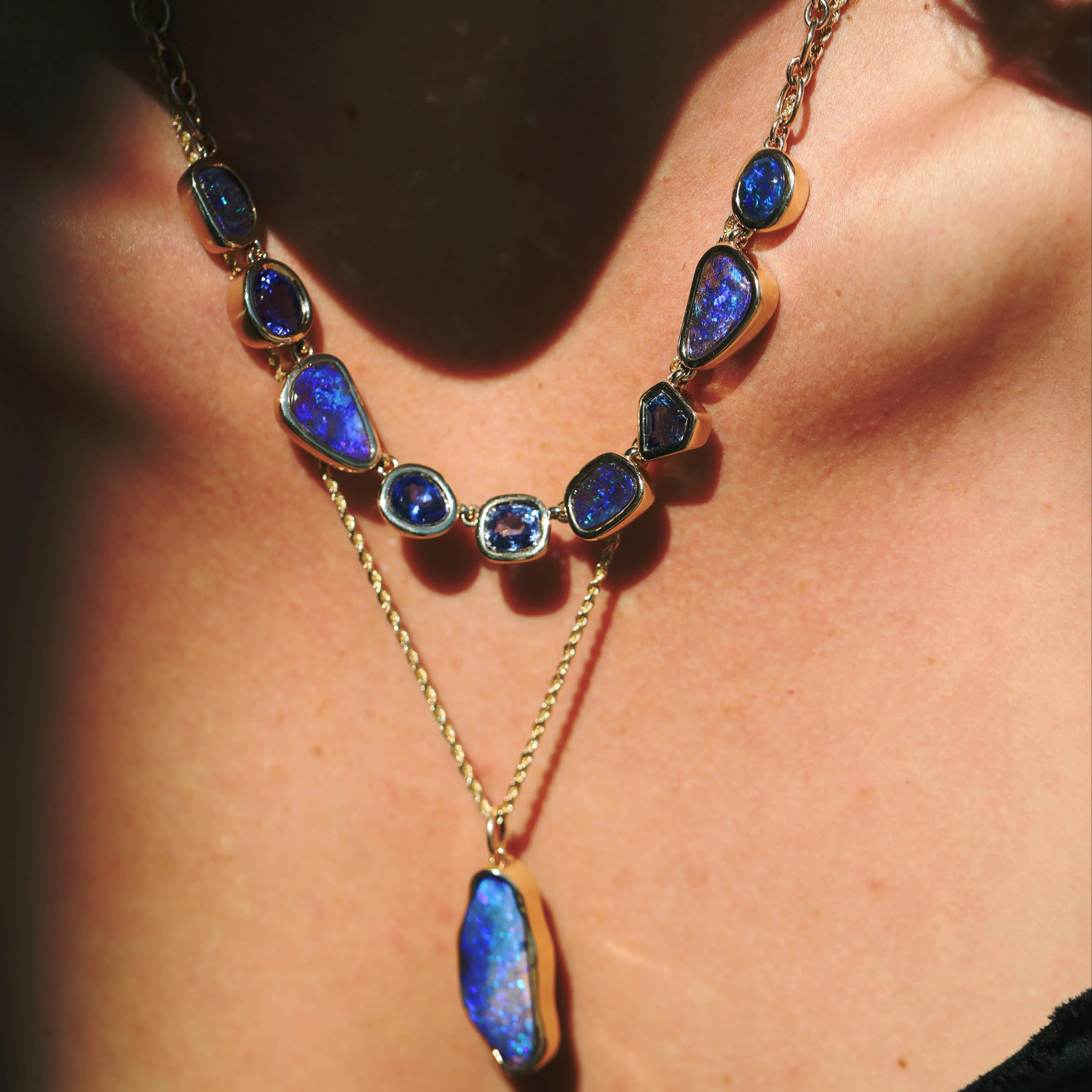 Necklace with blue gemstones and gold chain worn by a person