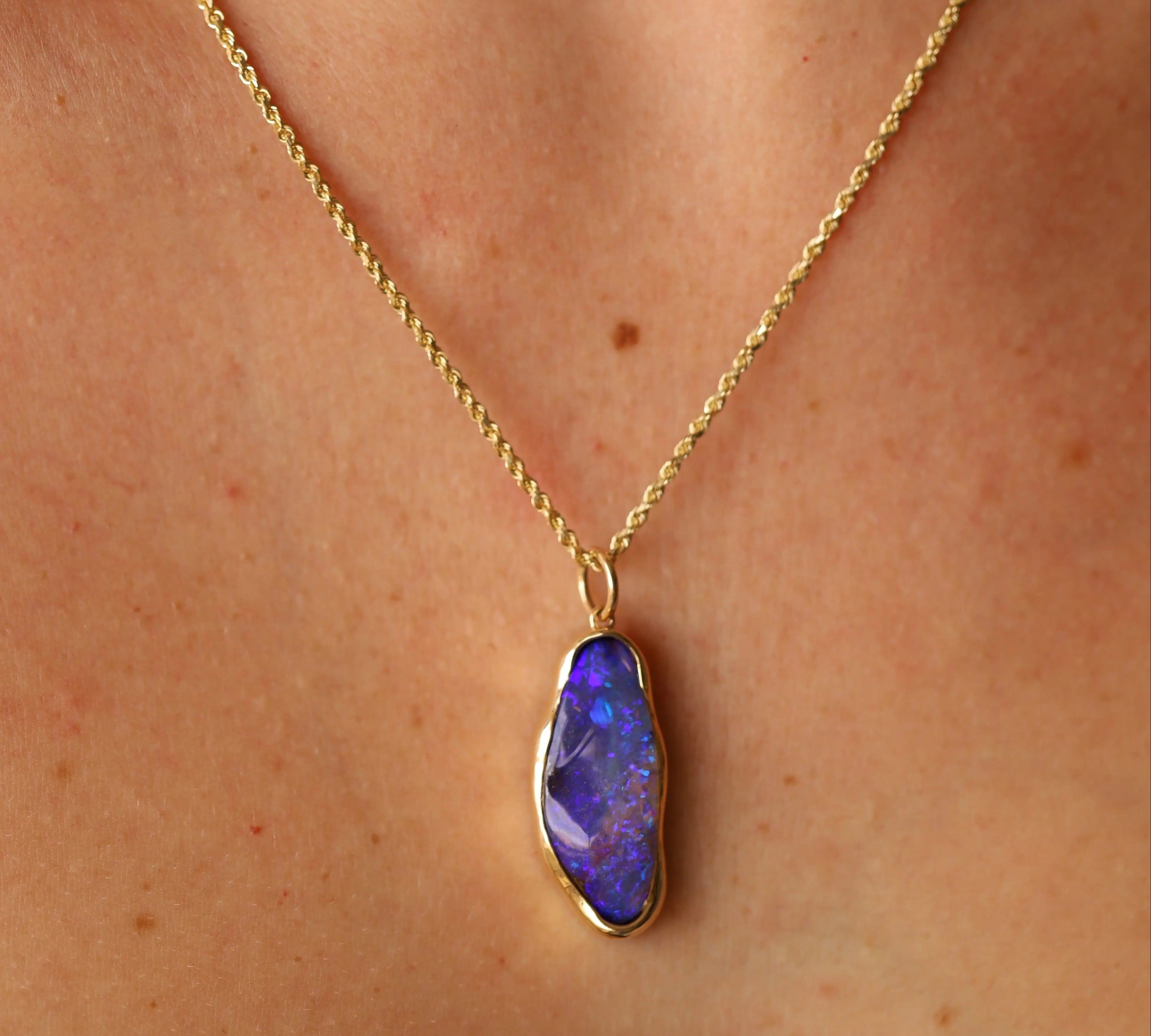 Gold necklace with a purple pendant on a person's neck