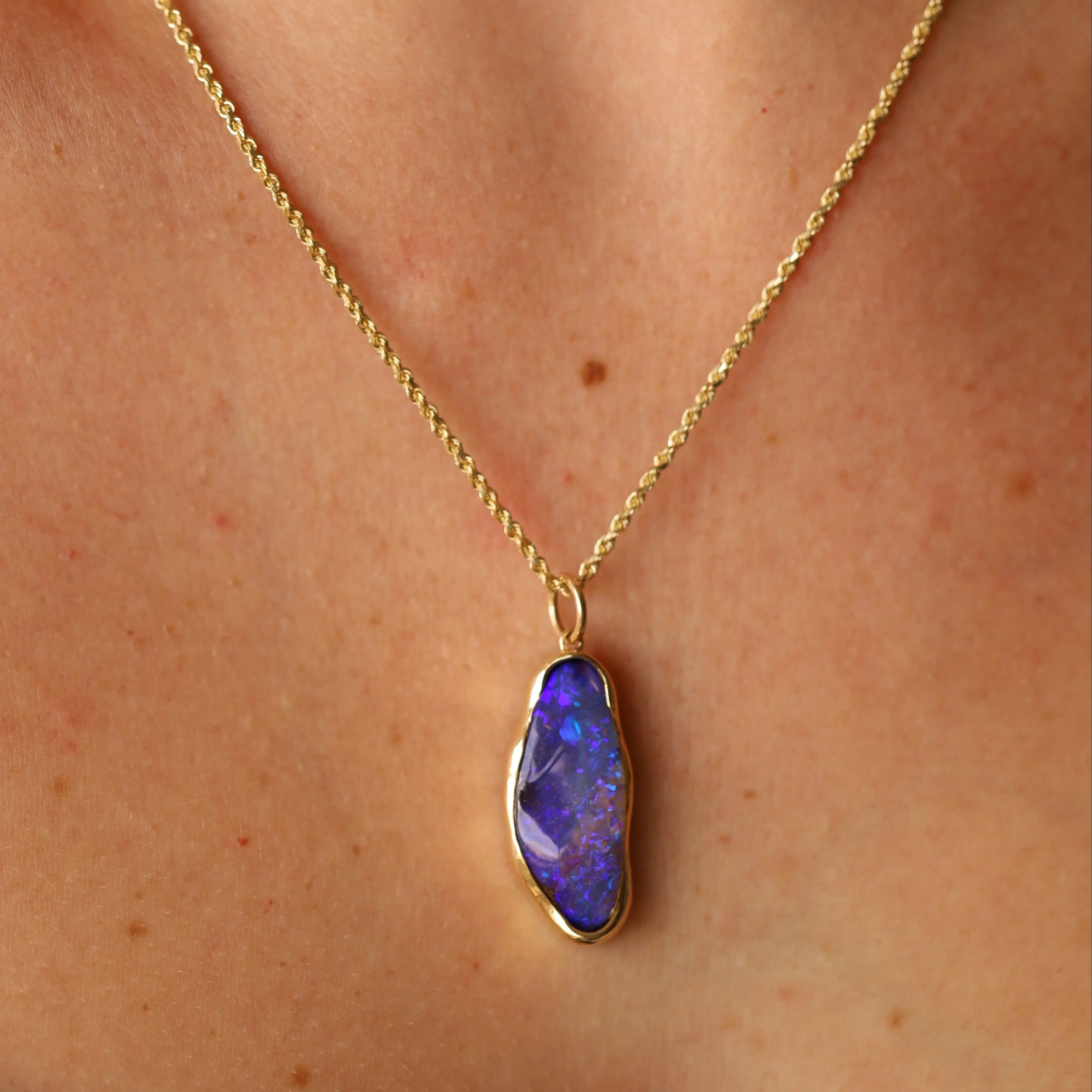 Gold necklace with a purple pendant on a person's neck