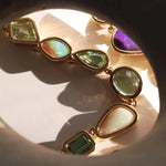 Gold necklace with colorful gemstones on a reflective surface