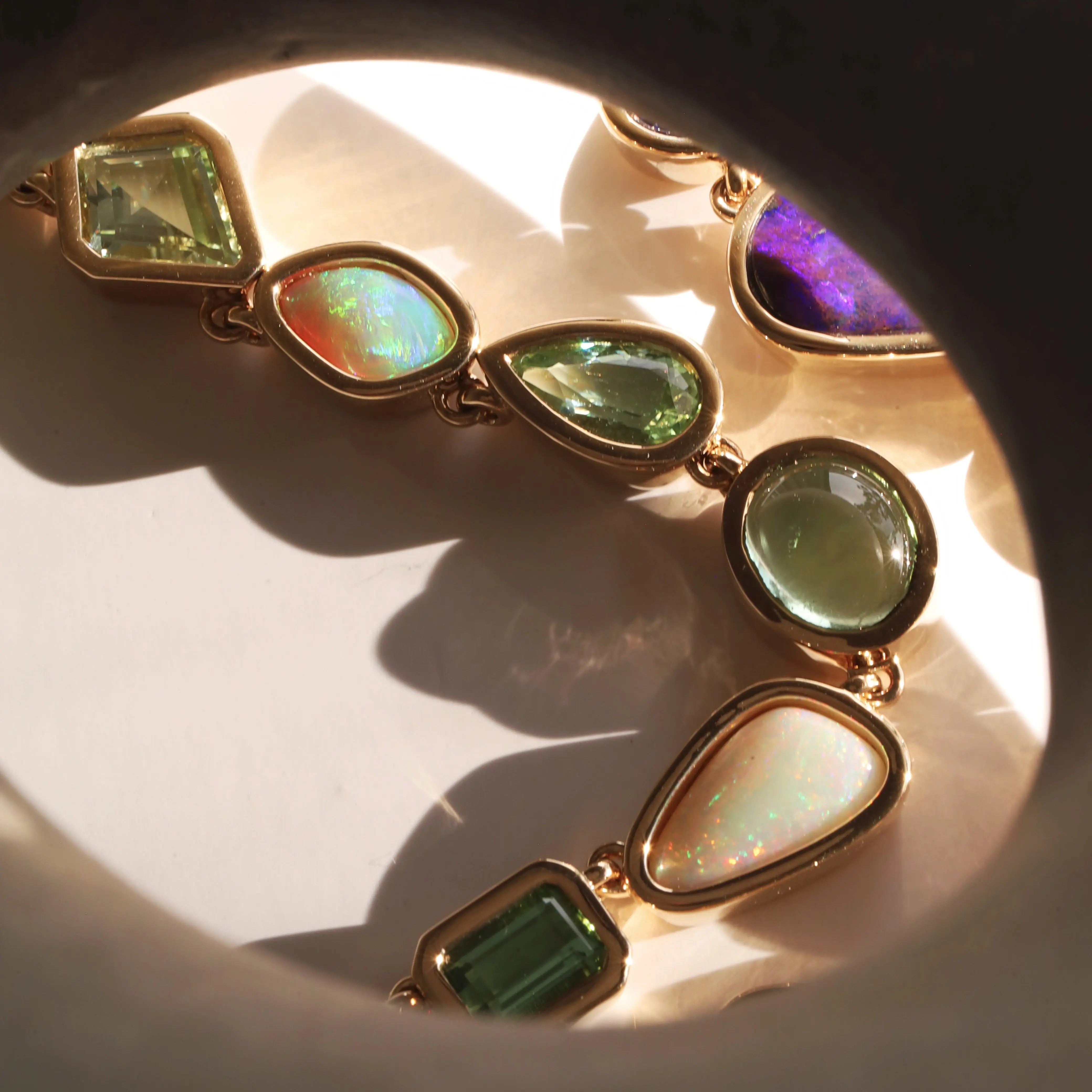 Gold necklace with colorful gemstones on a reflective surface