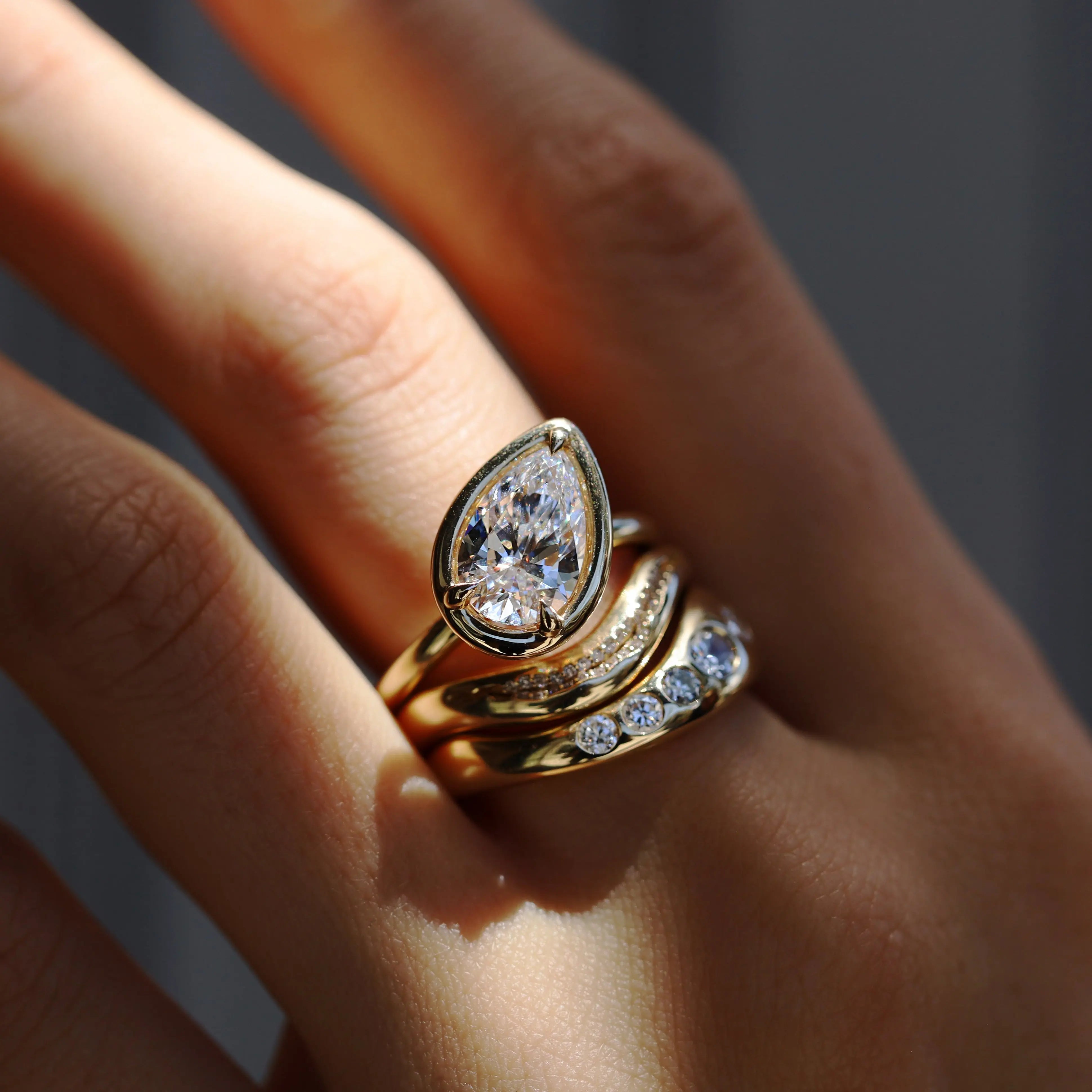 Gold ring with a diamond on a person's finger against a neutral background
