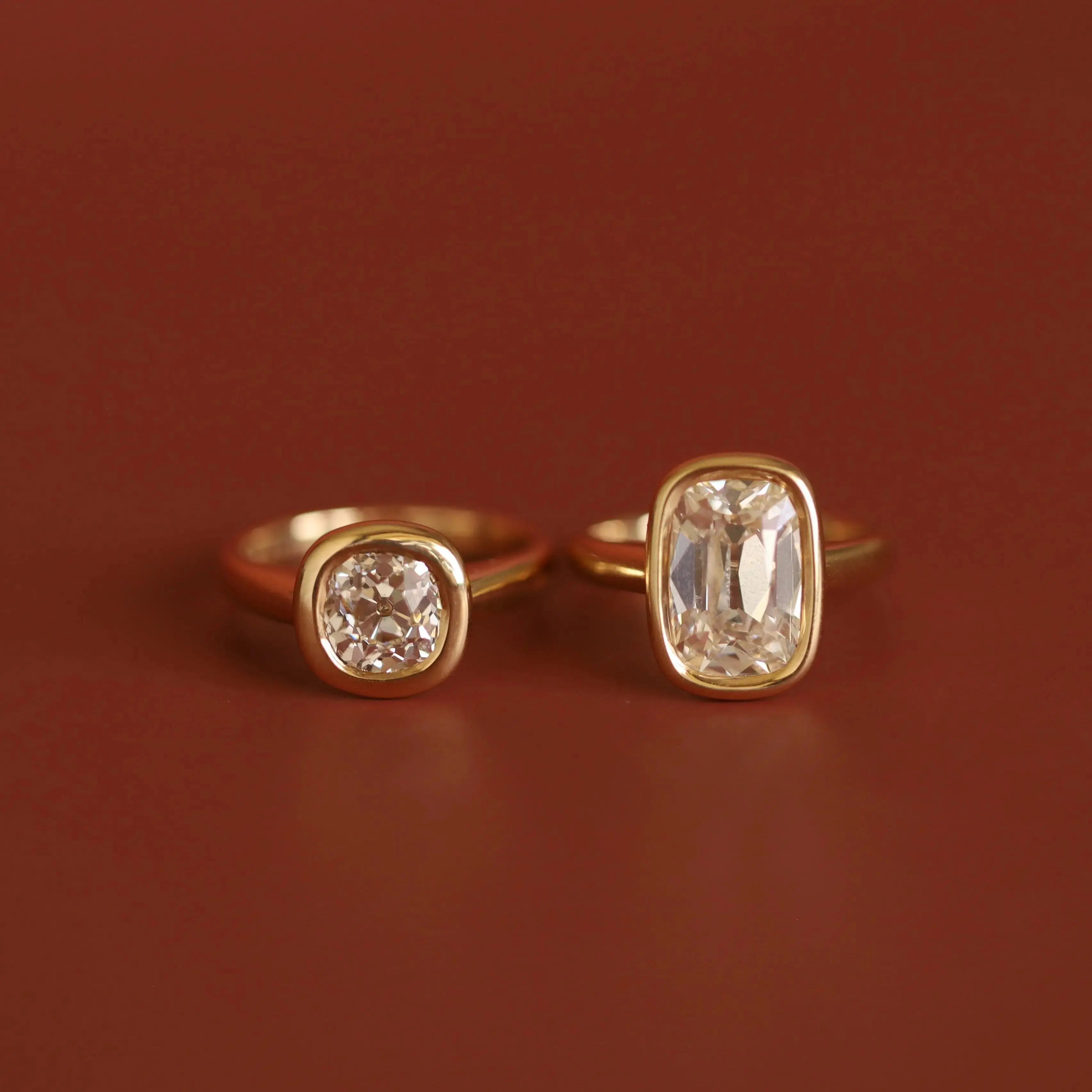 Two gold rings with bezel-set diamonds on a brown background