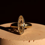 elongated diamond yellow gold ring on a dark background 