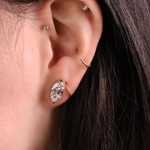 Close-up of an ear with diamond earrings and a gold ring.