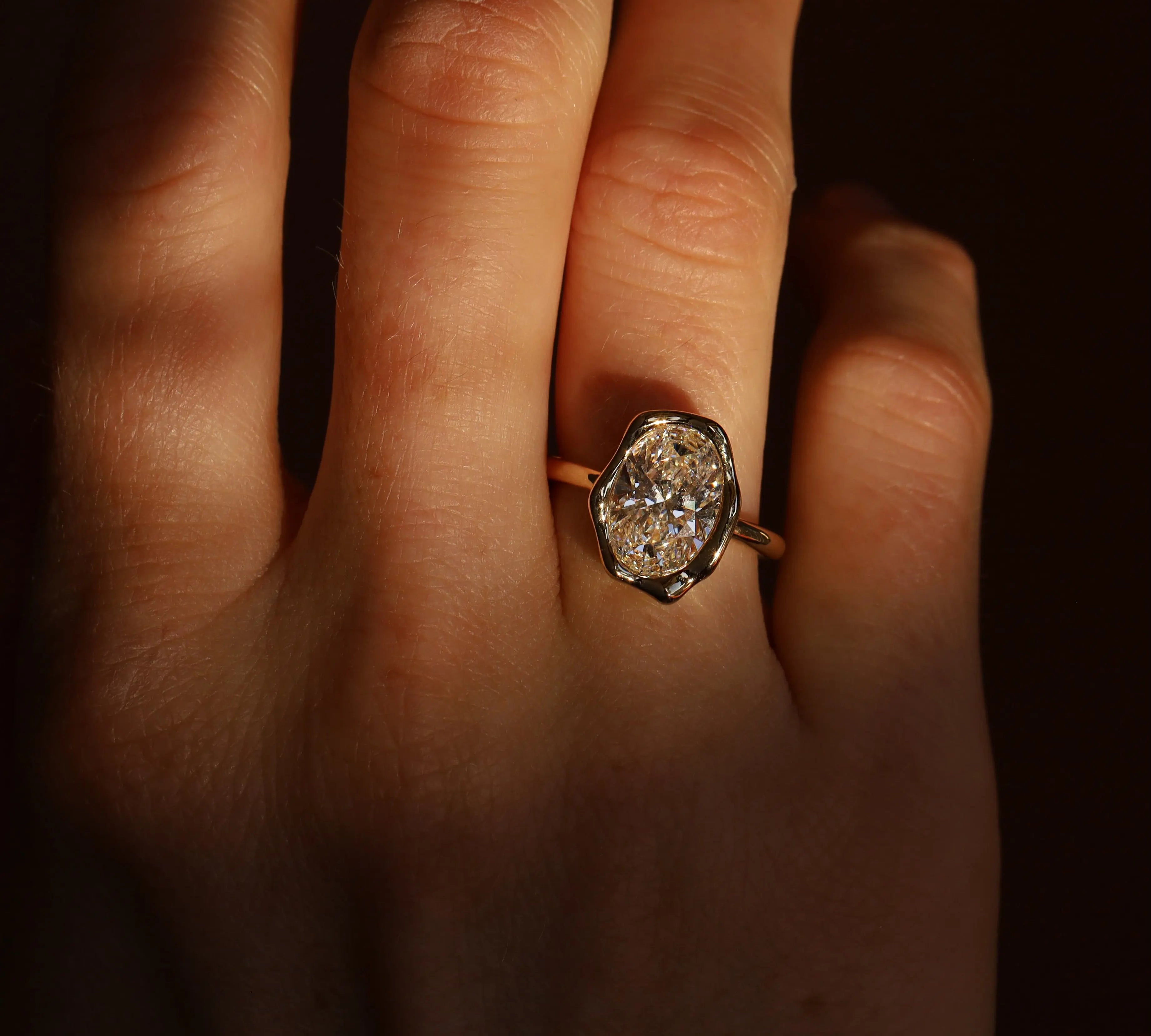 Close-up of a hand wearing a diamond ring with a dark background