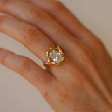Gold ring with a large diamond on a hand against a neutral background