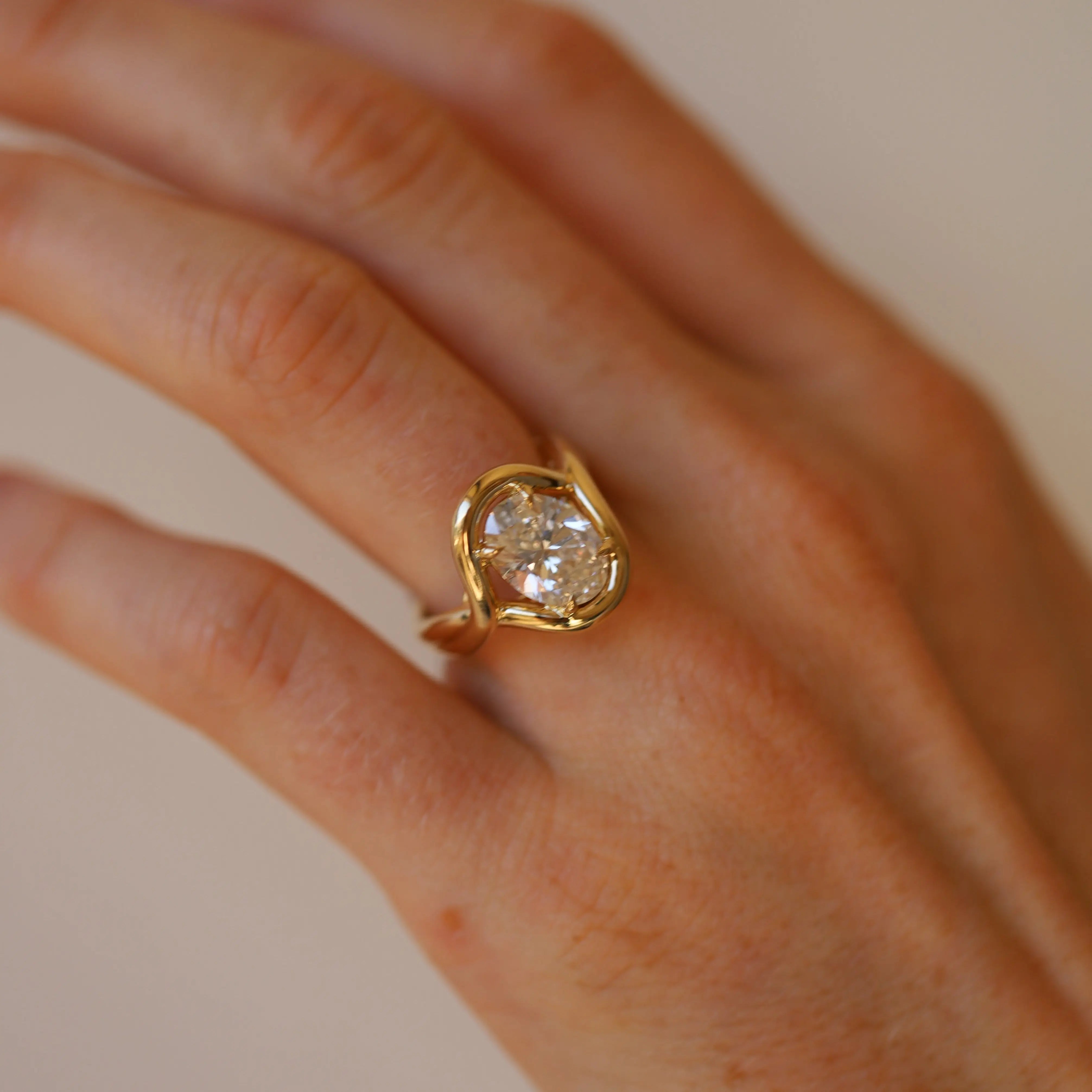 Gold ring with a large diamond on a hand against a neutral background