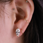 Close-up of an ear with gold hoop earrings and a marquise-shaped earring.