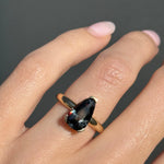 Ring with a large gemstone on a finger against a dark background