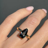 Ring with a large gemstone on a finger against a dark background