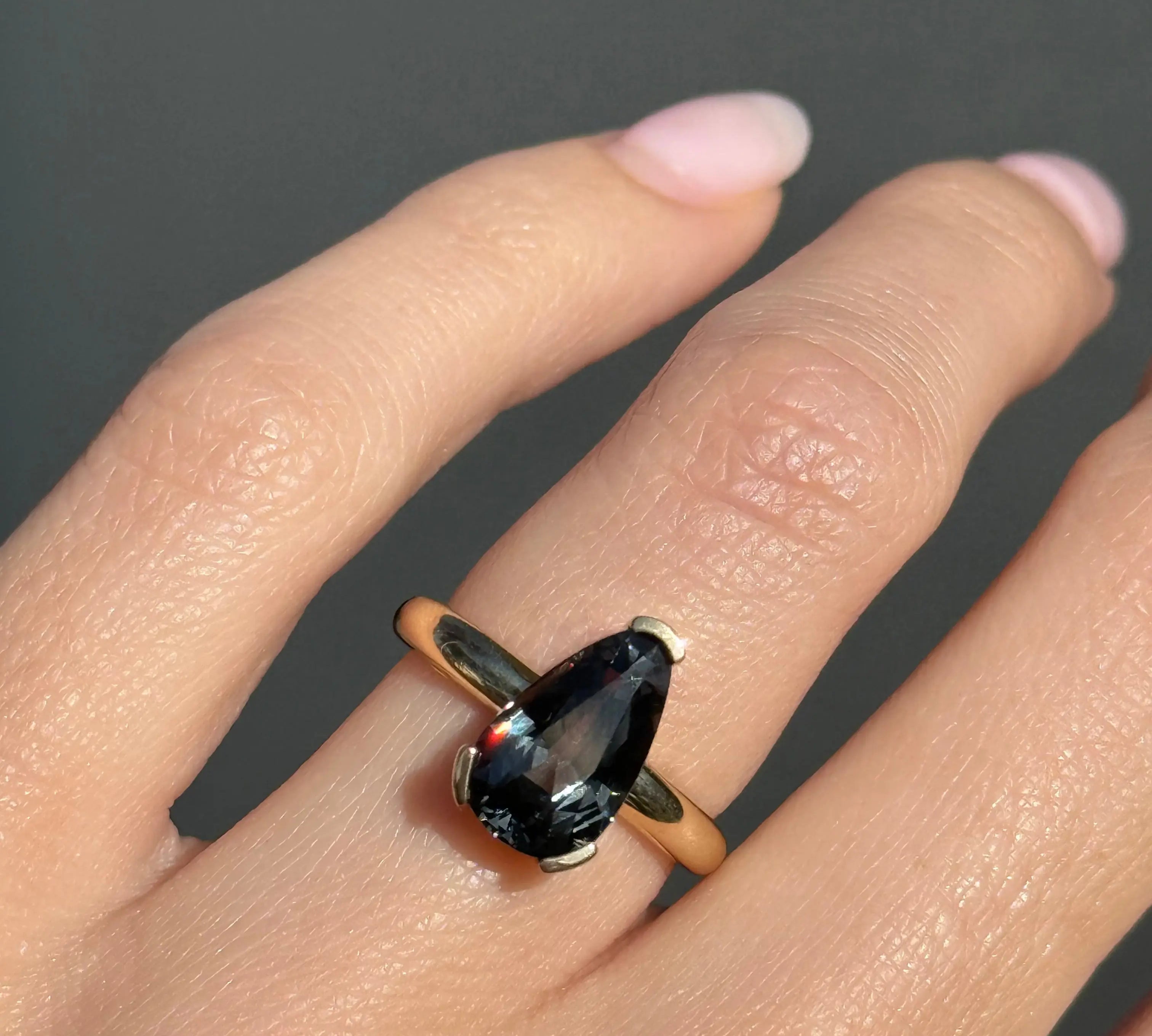 Ring with a large gemstone on a finger against a dark background