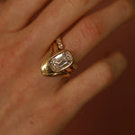 Gold ring with a diamond on a person's finger against a blurred background