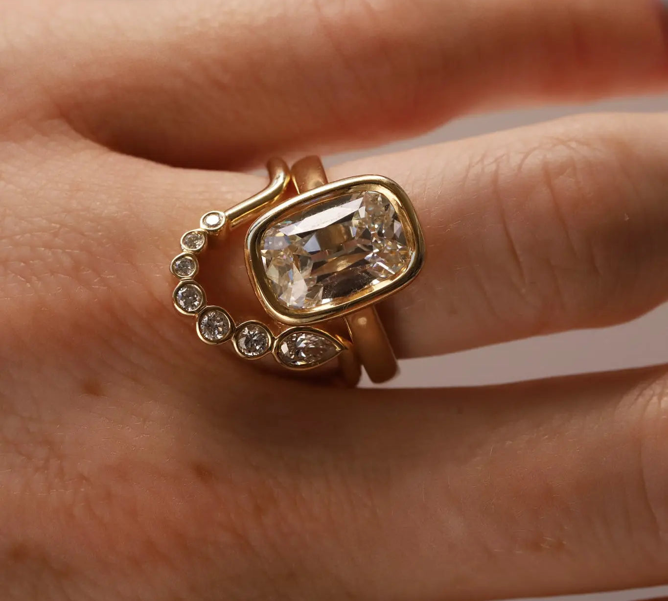 Gold diamond ring stacked with diamond band on person's hand, close up