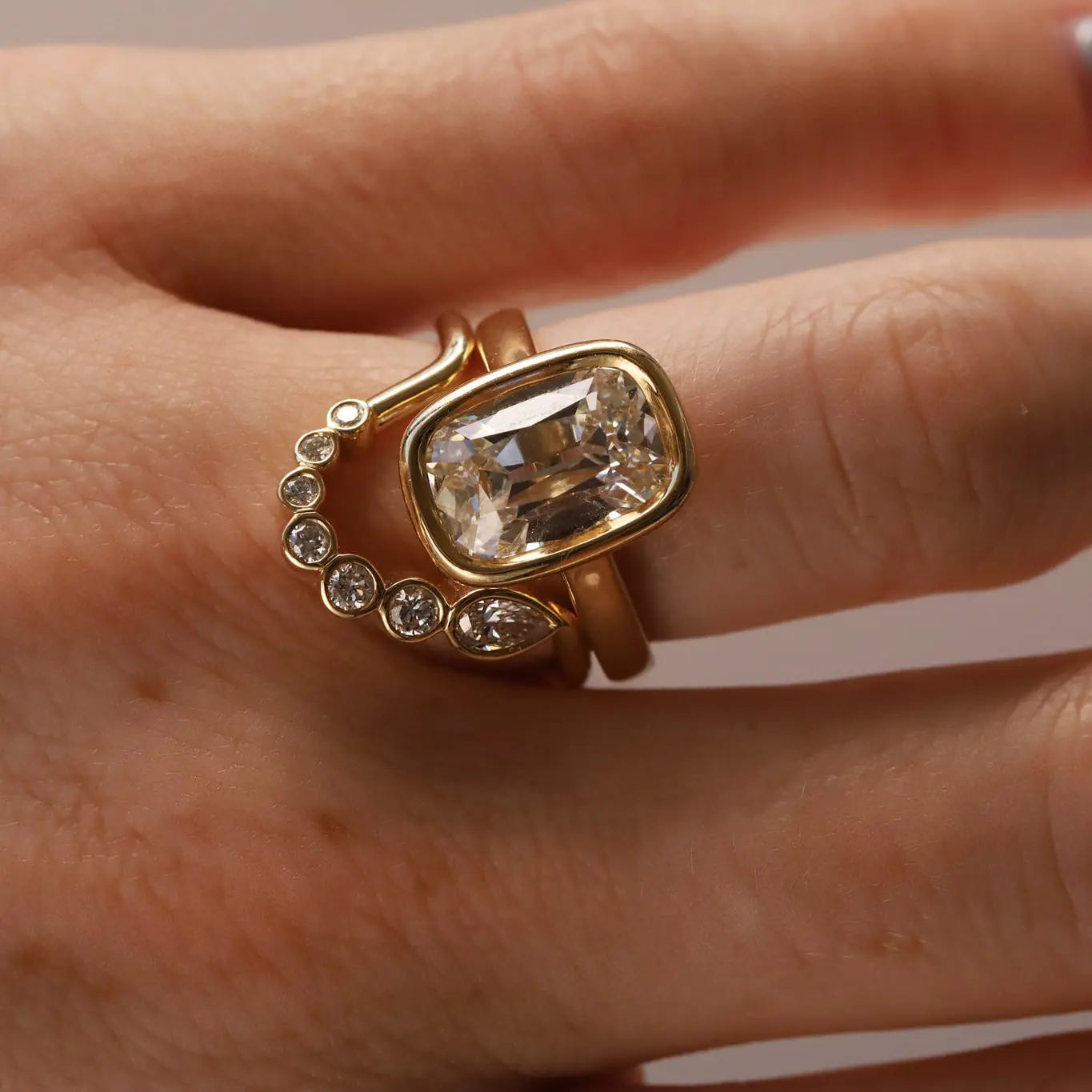 Gold diamond ring stacked with diamond band on person's hand, close up