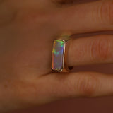 Opal ring on a finger with a neutral background