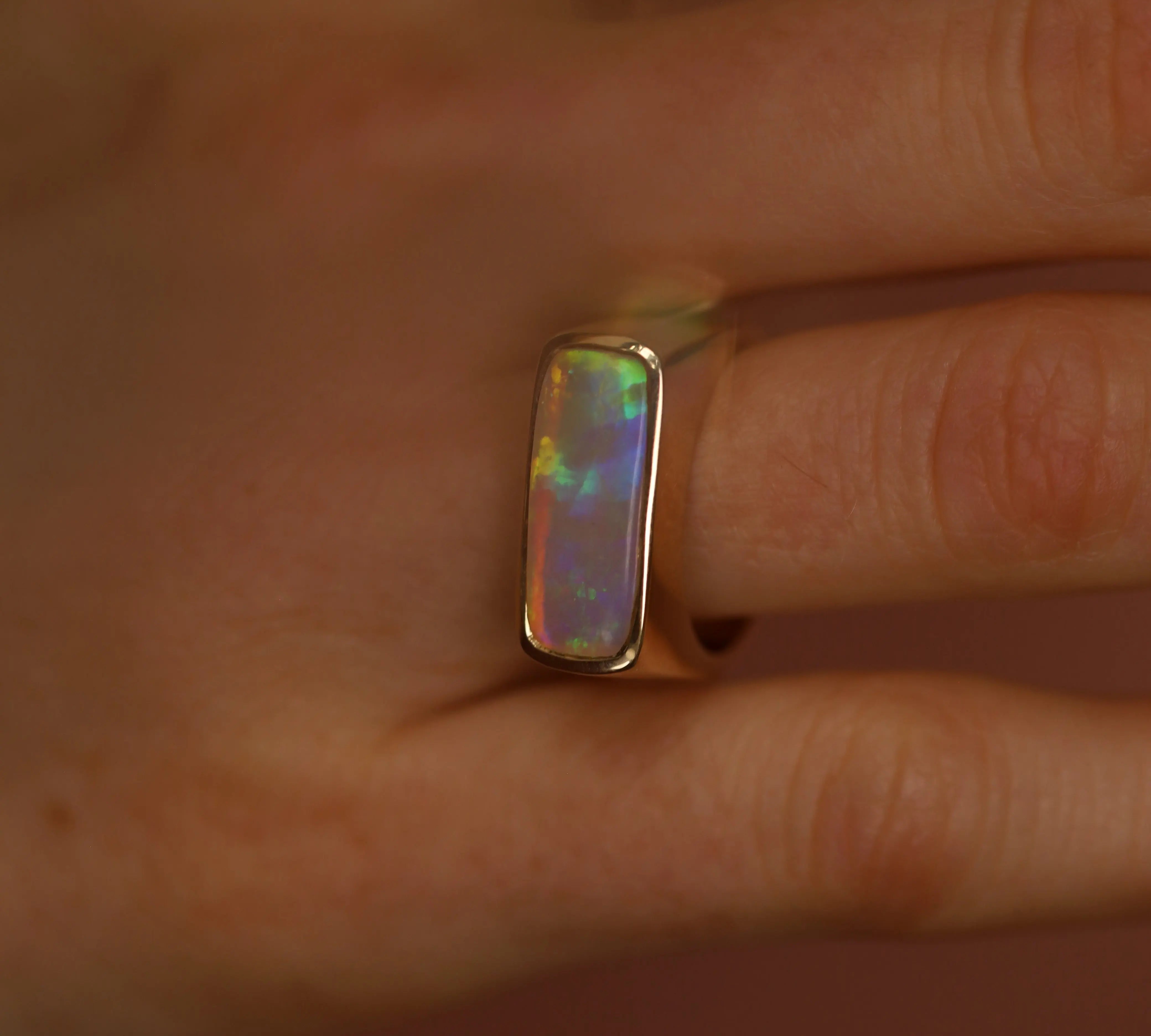 Opal ring on a finger with a neutral background