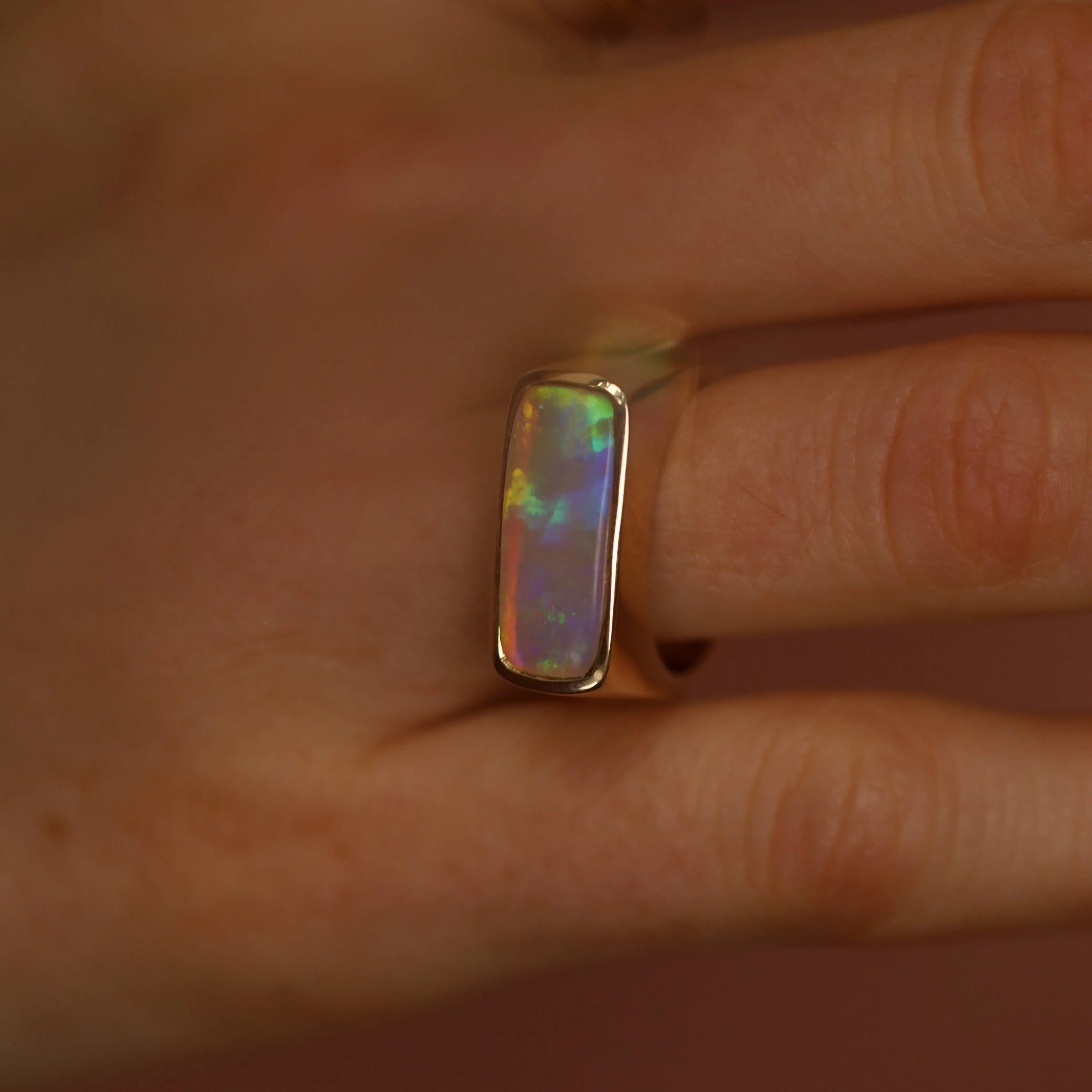 Opal ring on a finger with a neutral background