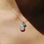 Necklace with an opal pendant and small diamond on a person's neck