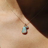 Necklace with an opal pendant and small diamond on a person's neck