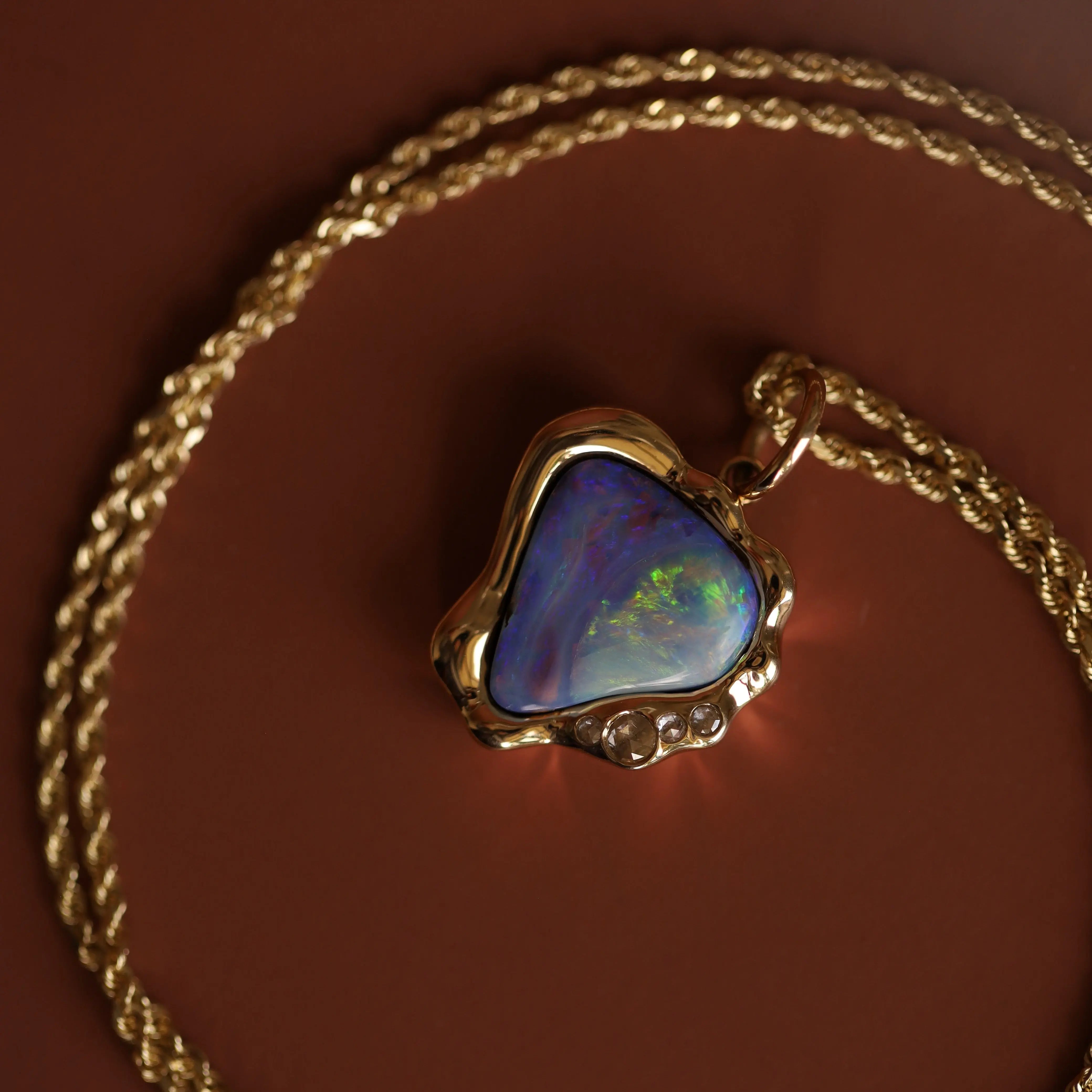 Opal pendant on a gold chain against a brown background
