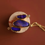 Jewelry with purple blue opals and gold accents on a brown background