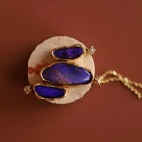 Jewelry with purple blue opals and gold accents on a brown background