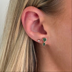 Close-up of an ear wearing a green earring with a white background