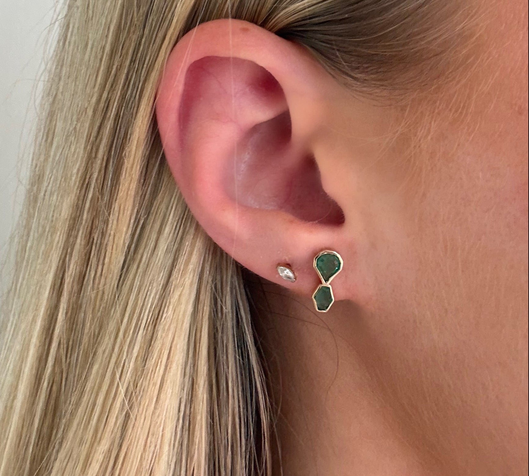 Close-up of an ear wearing a green earring with a white background
