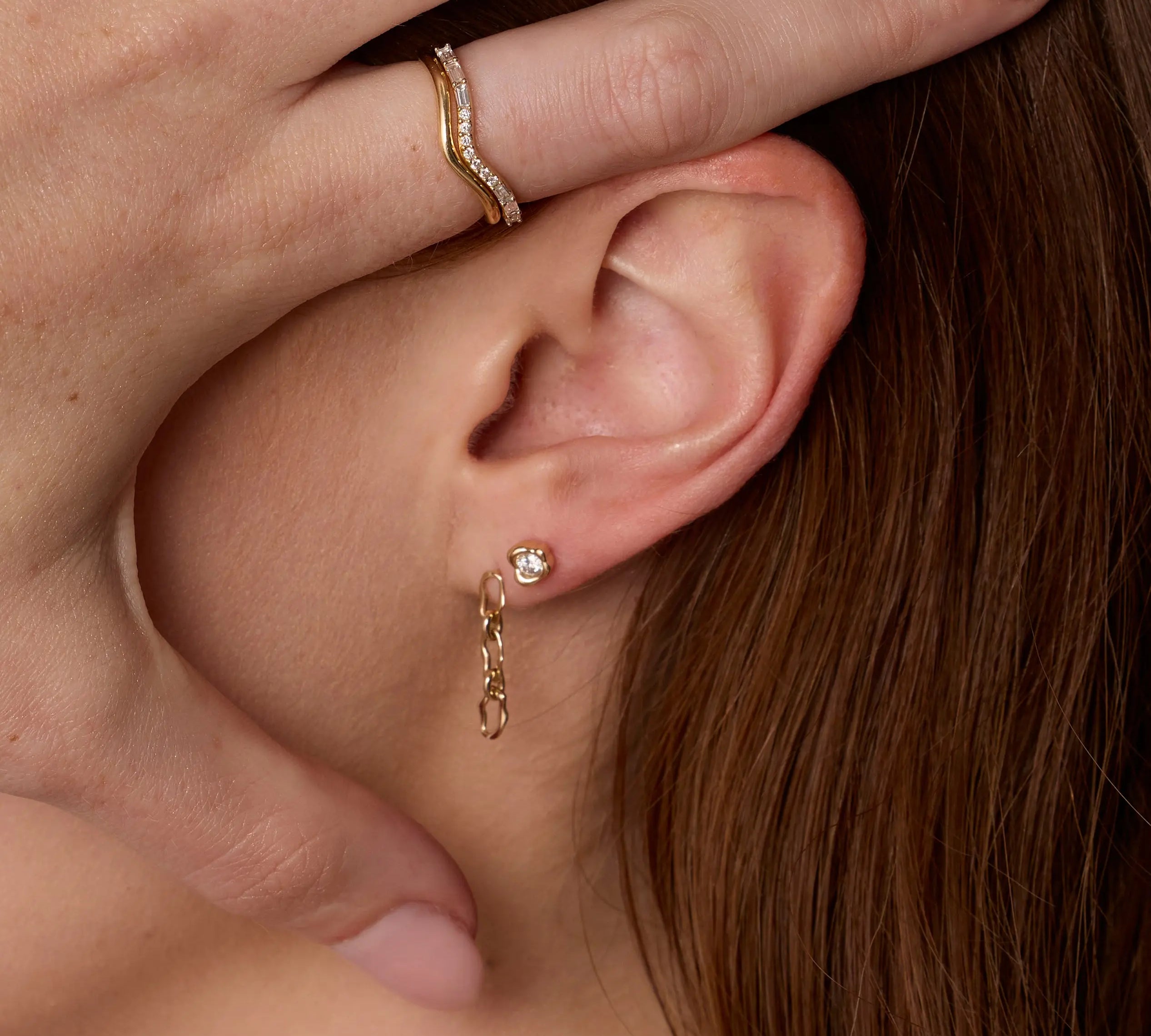 Close up of woman's ear with 6mm Sculpted Link Gold Earrings + White Diamond Abstract Bezel Studs