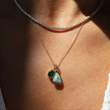 Necklace with a pendant featuring two green gemstones on a person's neck.