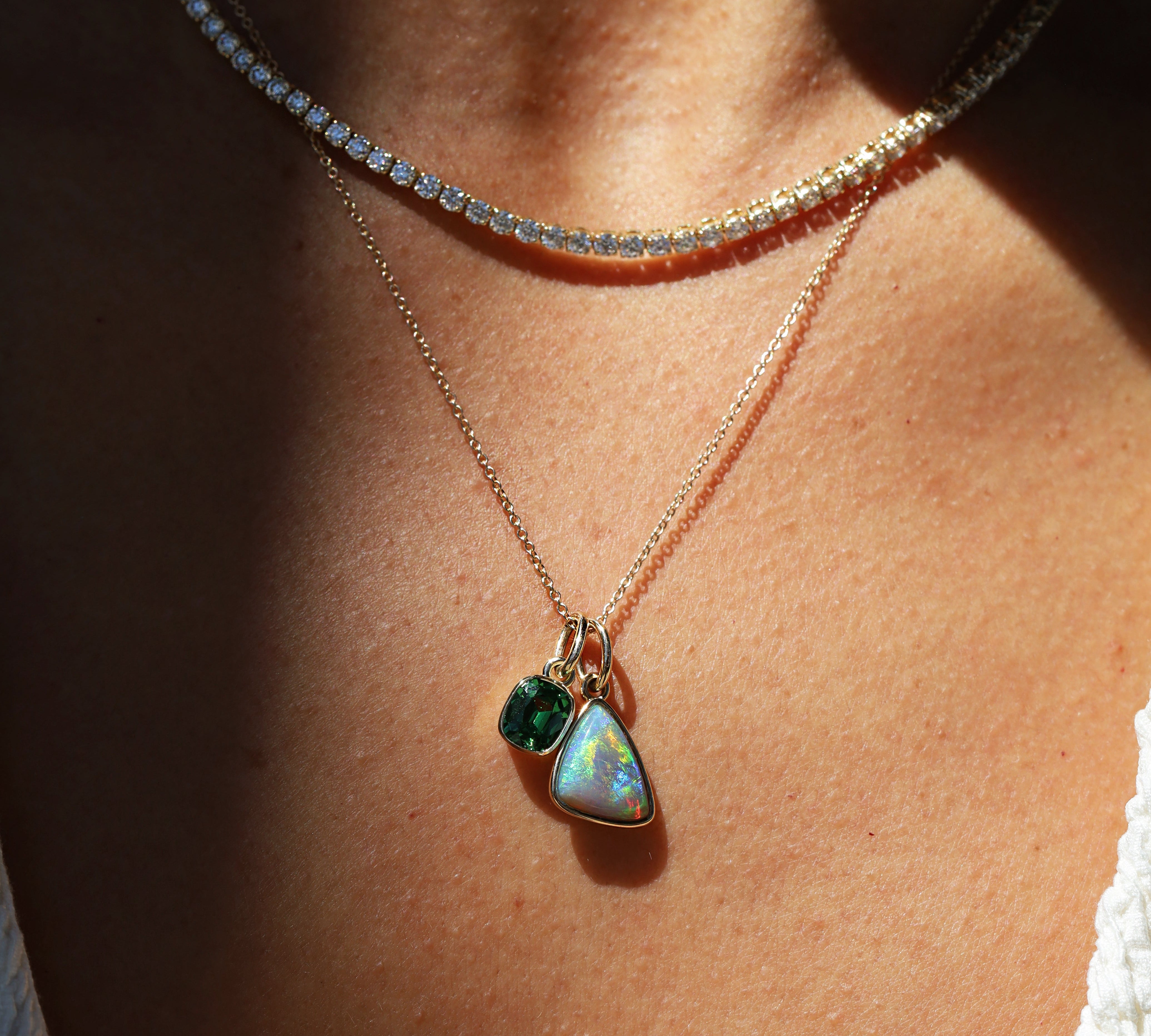 Necklace with a pendant featuring two green gemstones on a person's neck.