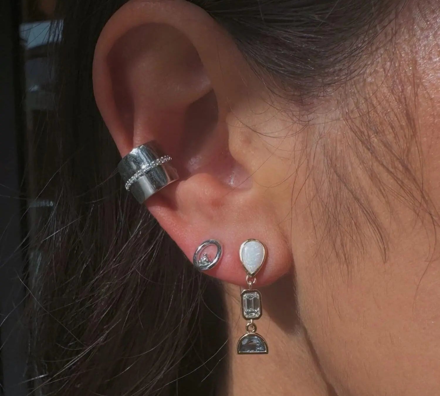 Image of Marrow Fine earrings on ear. The ear stack has a white gold small circle stud, a white gold ear cuff with a thin row of diamonds, and an opal dangle earring.  