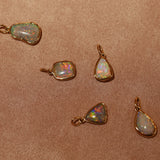 Opal pendants with gold settings on a brown fabric background