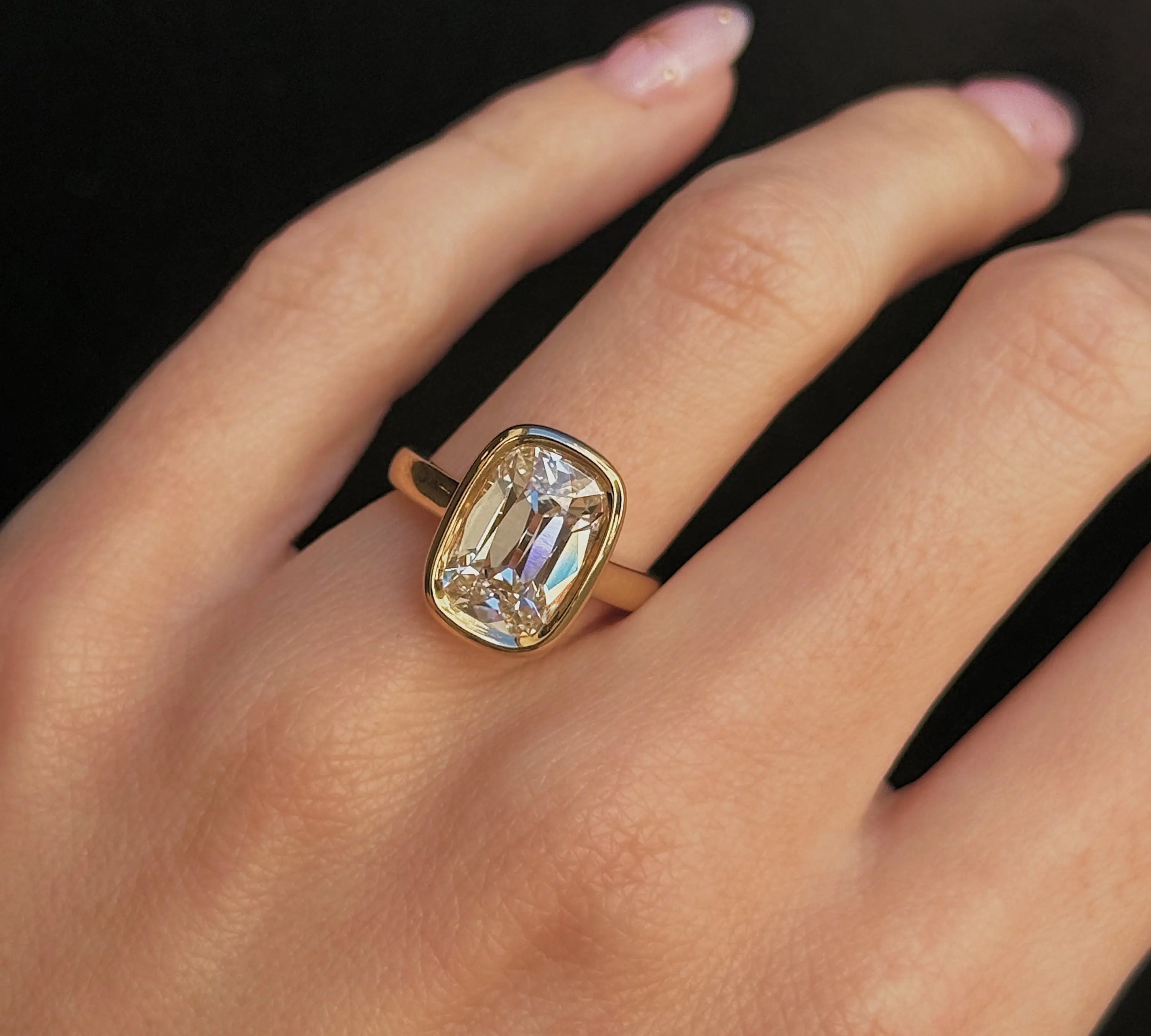 Gold ring with a large diamond on a hand against a black background