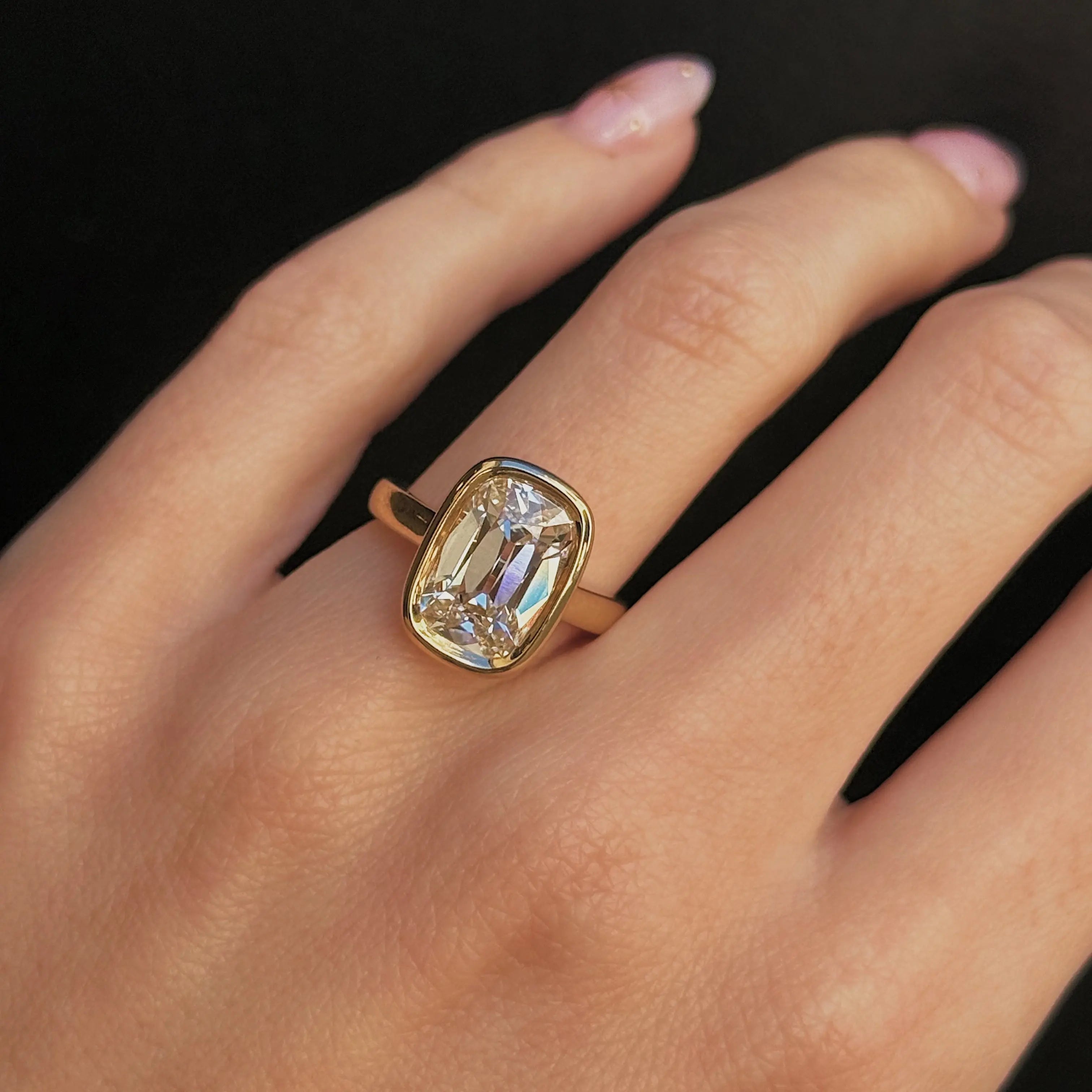 Gold ring with a large diamond on a hand against a black background