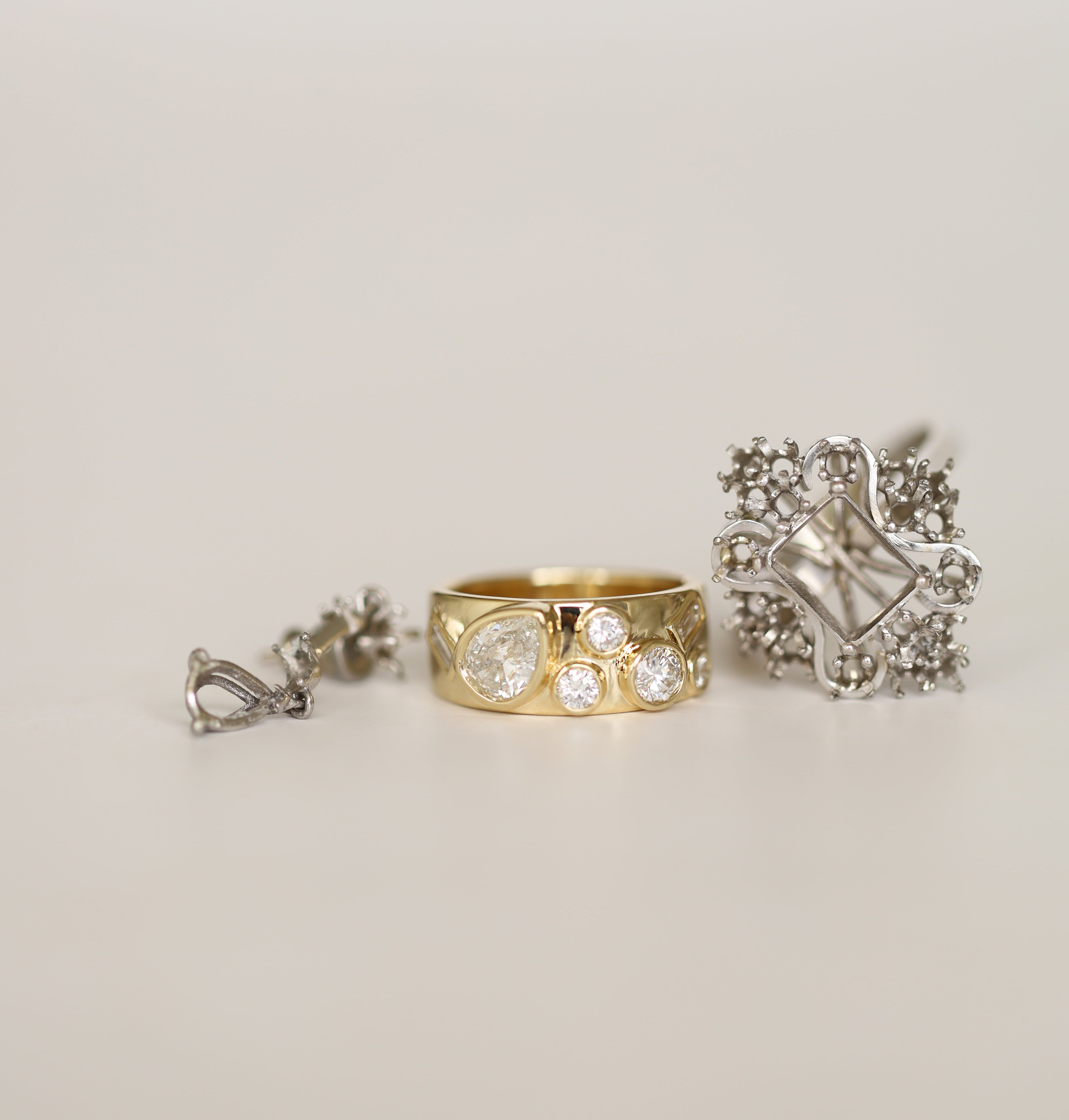 Gold ring with floral design and silver ring with decorative band on a light gray background