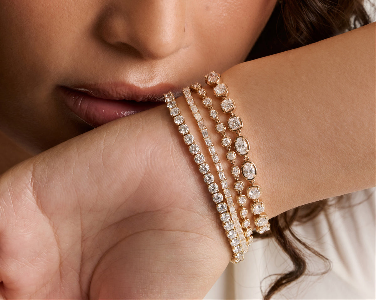 Stack of gold and diamond tennis bracelets worn on the wrist