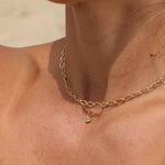 Gold necklace with a small pendant on a person's neck against a neutral background