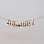 Gold necklace with colorful gemstones on a light gray background