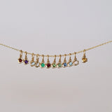 Gold necklace with colorful gemstones on a light gray background