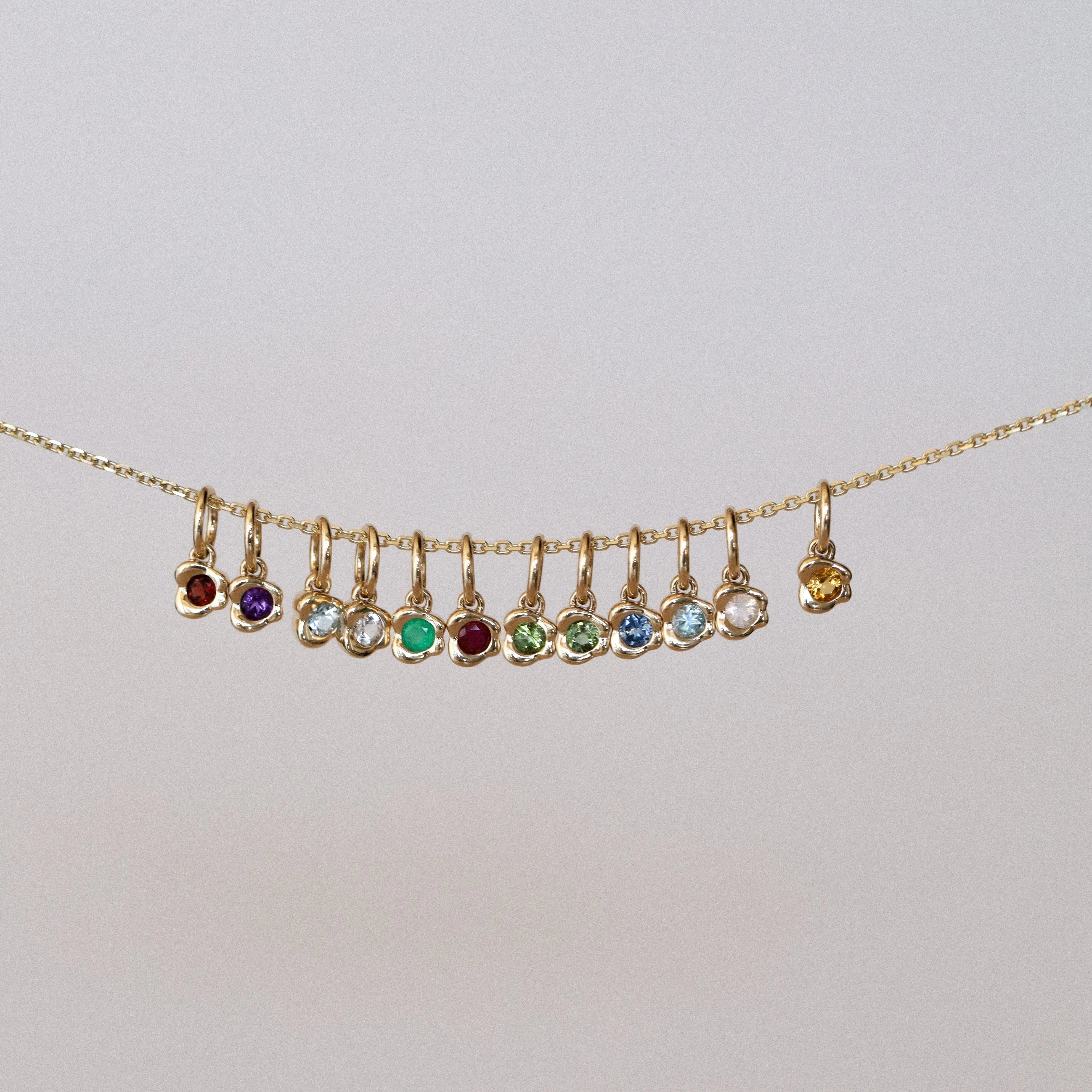 Gold necklace with colorful gemstones on a light gray background